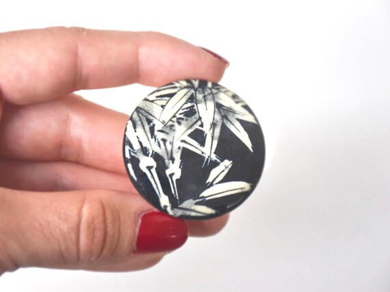 Kiyomizu Porcelain Bamboo Leaf Brooch held next to a hand to demonstrate its round shape and scale