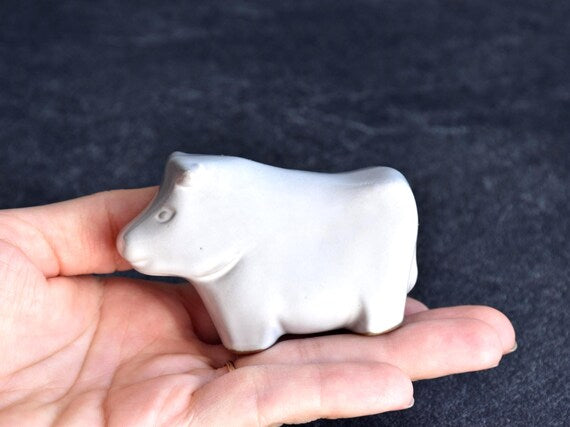 Japanese ceramic cow figurine shown held in a hand for scale