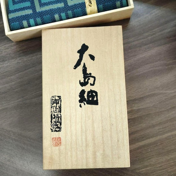 Oshima Tsumugi silk coin purse wooden box lid featuring bold black Japanese calligraphy