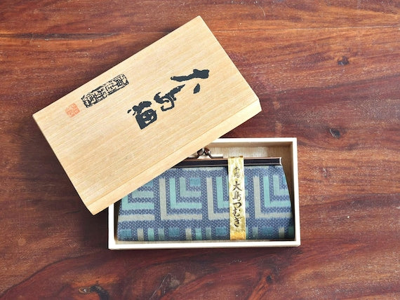Oshima Tsumugi silk coin purse shown inside its original wooden box with lid aside