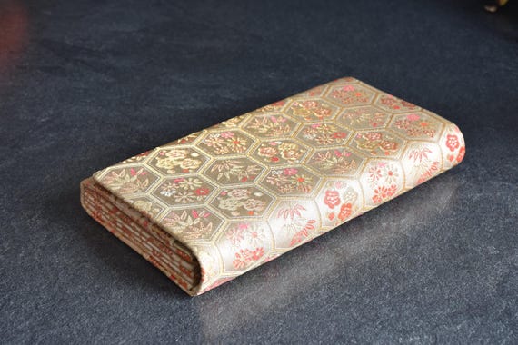 Hexagonal Floral Kimono Clutch resting on dark surface viewed from side