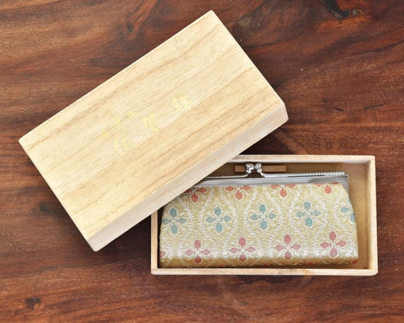 Saga Nishiki coin purse resting neatly inside its original wooden box on a wooden surface