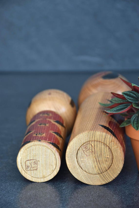 Takahashi Hashime kokeshi pair showing the flat wooden base with stamped maker signatures