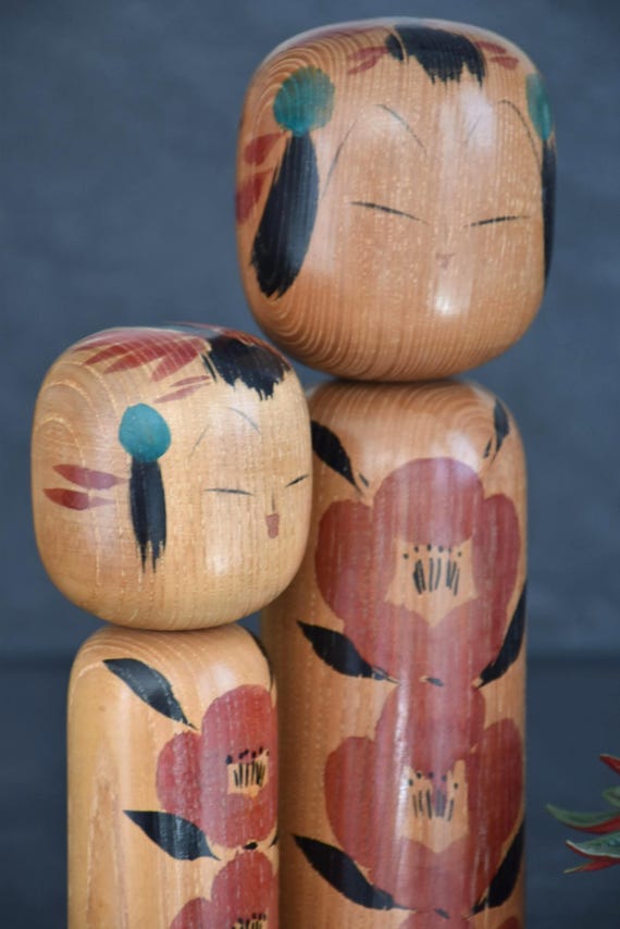 Takahashi Hashime kokeshi pair angled view focusing on the minimalist facial details and hair
