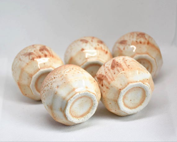Bottom view of five handmade Shino ware ceramic guinomi sake cups showing their bases