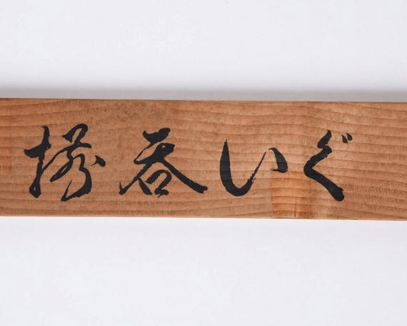 Close-up detail of the black Japanese calligraphy text written on the wooden storage box lid
