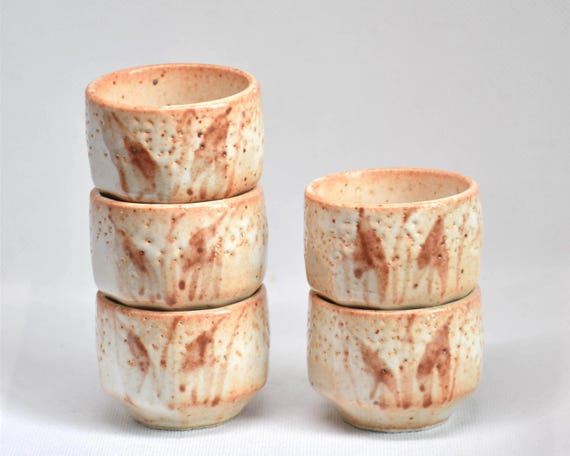 Set of 5 Japanese ceramic guinomi sake cups stacked in two columns showing orange skin texture