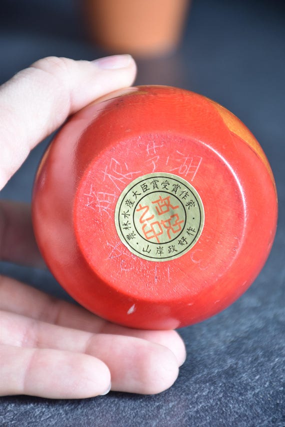 Yamagishi Masayoshi sosaku kokeshi base held in hand displaying maker award sticker
