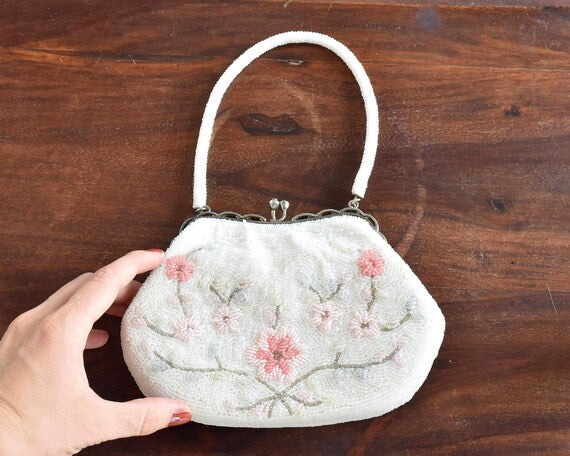 Japanese Floral Beaded Clutch Bag held by a hand to demonstrate its size against a dark wooden surface