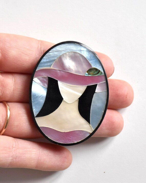 Raden shell inlay brooch showing size next to a hand