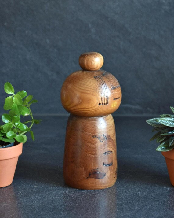 Kazuo Takamizawa kokeshi doll side profile displaying carved hair lines and floral pattern