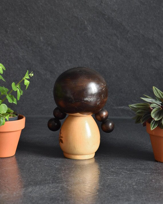 Jiro Tsuda kokeshi doll shown from the back with round pigtails and simple wooden body