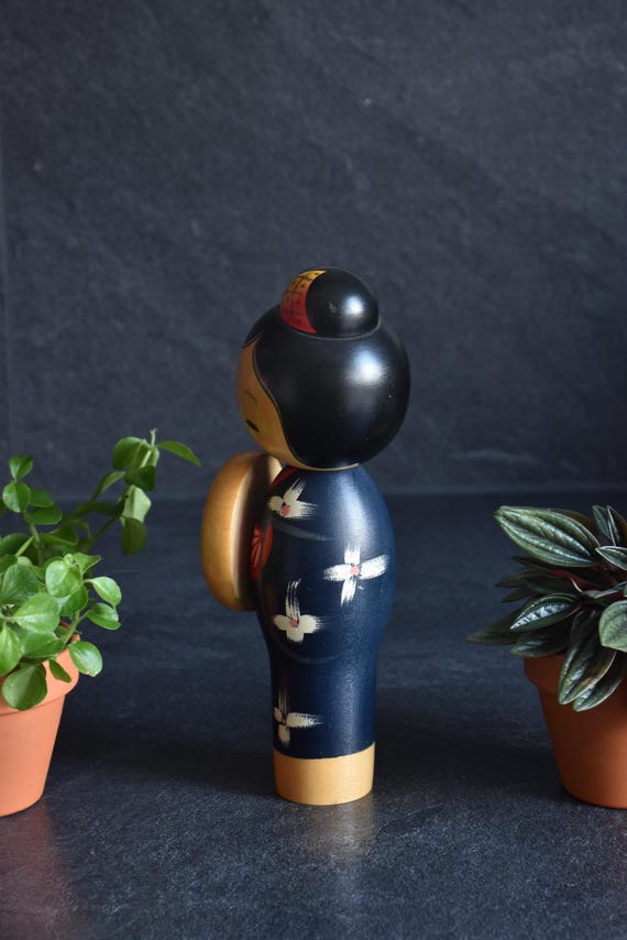 Miyashita Hajime kokeshi doll showing the painted white floral motifs on the deep blue kimono back