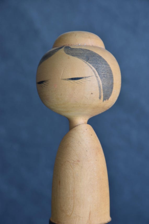 Sato Suigai kokeshi facial detail showing closed painted eyes and hair brushstrokes