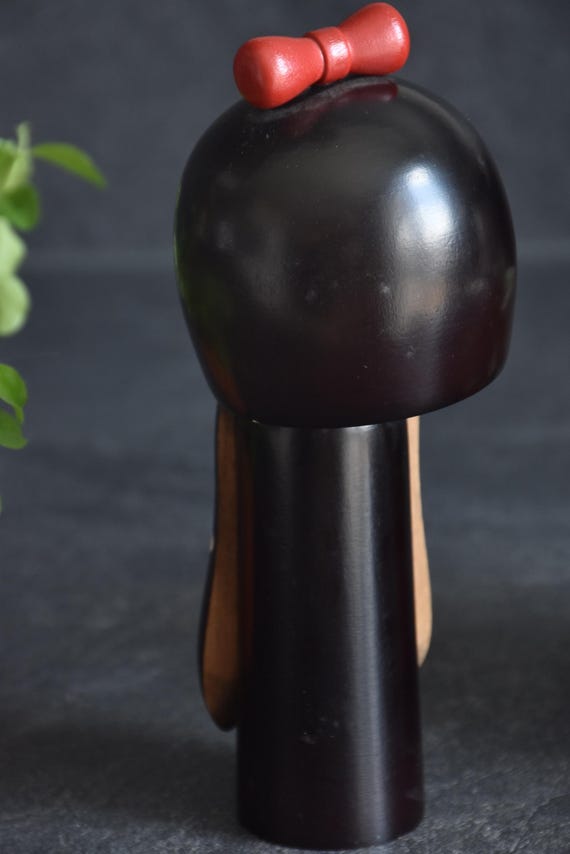 Hajime Miyashita When Flowers Bloom Kokeshi doll rear view focusing on the smooth dark finish