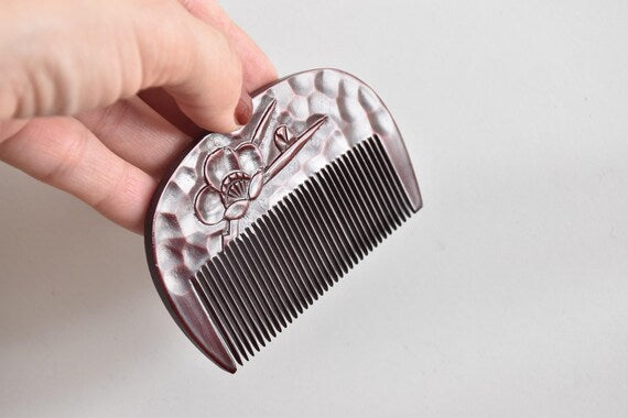Kamakura-Bori Plum Blossom Comb shown next to a hand for size comparison