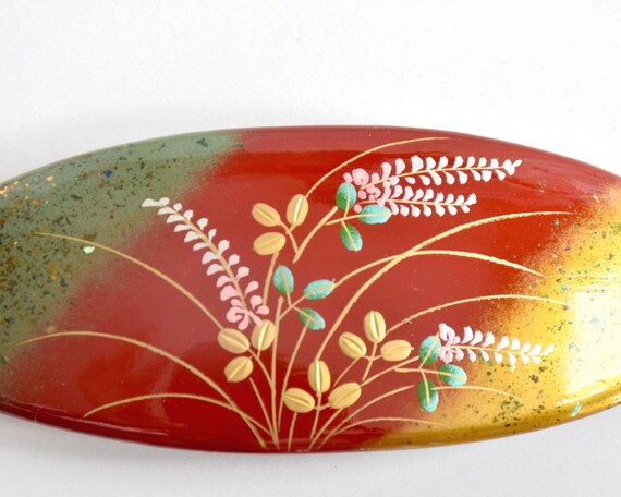 Maki-E Red Oval Barrette With Gold Floral macro view of the hand-applied gold powder clouds and floral details