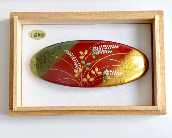 Maki-E Red Oval Barrette With Gold Floral displayed inside its open paulownia wood presentation box