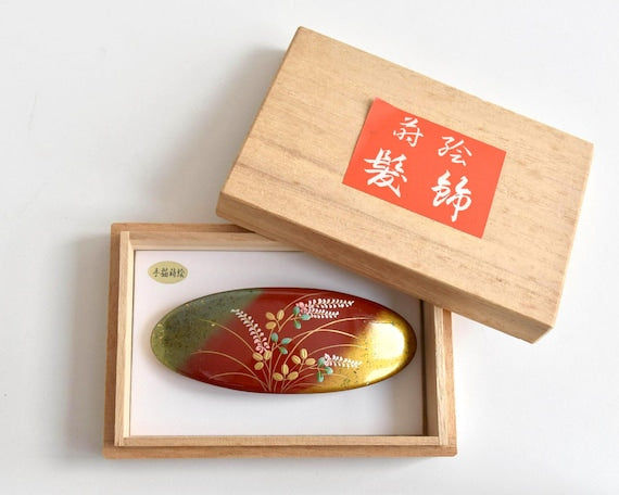 Maki-E Red Oval Barrette With Gold Floral design and traditional Japanese art details displayed in box
