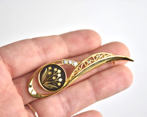 Amita Damascene Floral Brooch held next to a hand to show scale