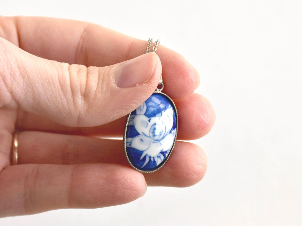 Japanese Cobalt Blue Floral Porcelain Pendant Necklace held in a hand showing close-up of pattern