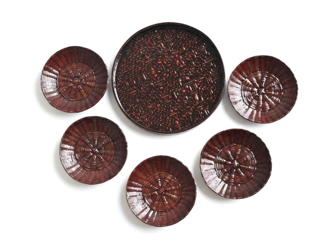 Rantai Shikki woven bamboo lacquer tray and five small plates arranged together on white