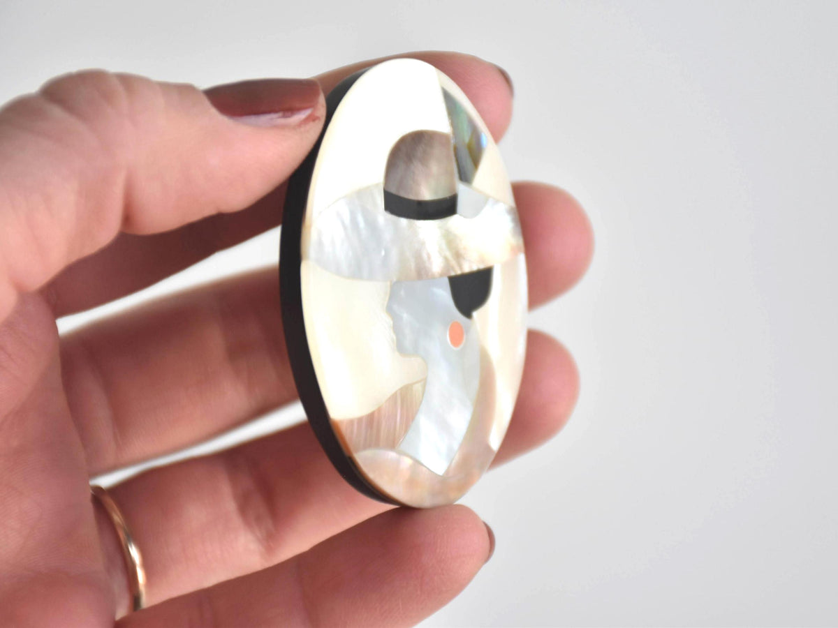 Raden Shell Inlay Portrait Brooch Woman With Hat viewed from the side in a hand