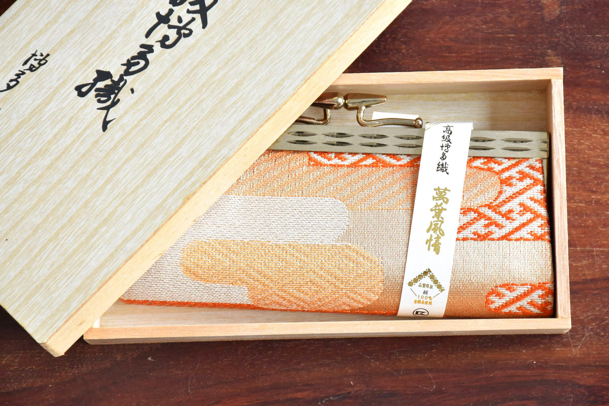 Hakata-Ori Silk Gamaguchi Coin Purse neatly placed inside its open wooden storage box with the lid tilted behind.