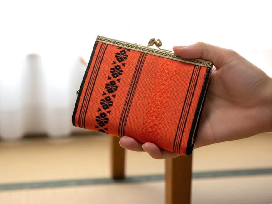 Vermilion Hakata-Ori Silk Clasp Coin Purse held in a hand to demonstrate its scale and size