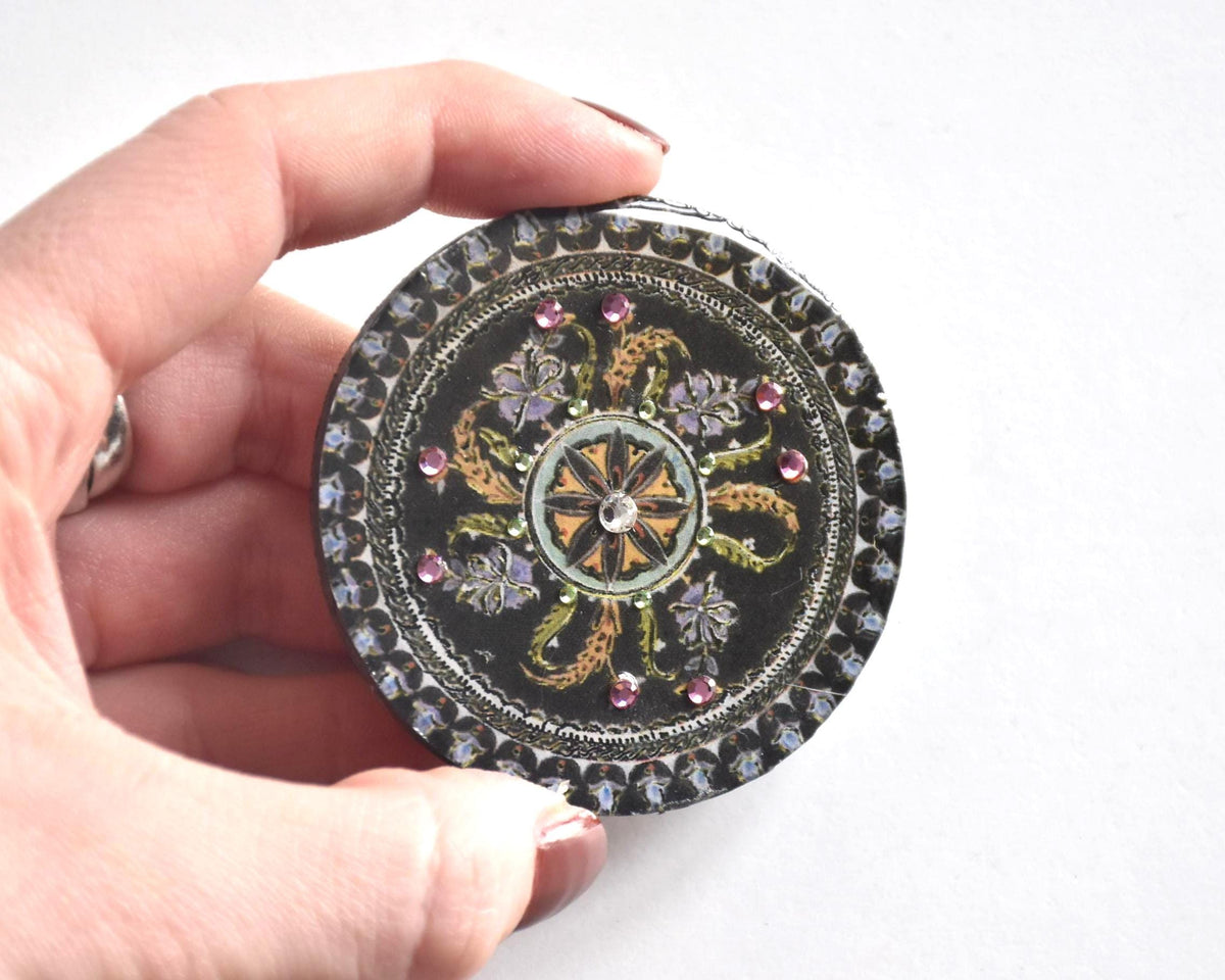 Japanese lacquerware floral brooch held in a hand to show relative size