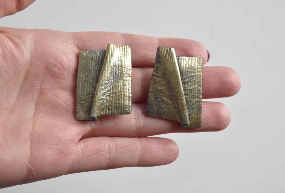 Matching clip-on earrings from the sculptural leather jewelry set shown in hand