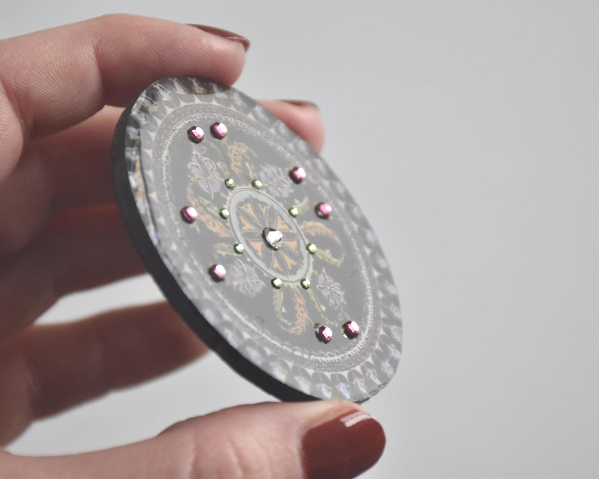 Japanese lacquerware floral brooch tilted to show surface texture and bead accents