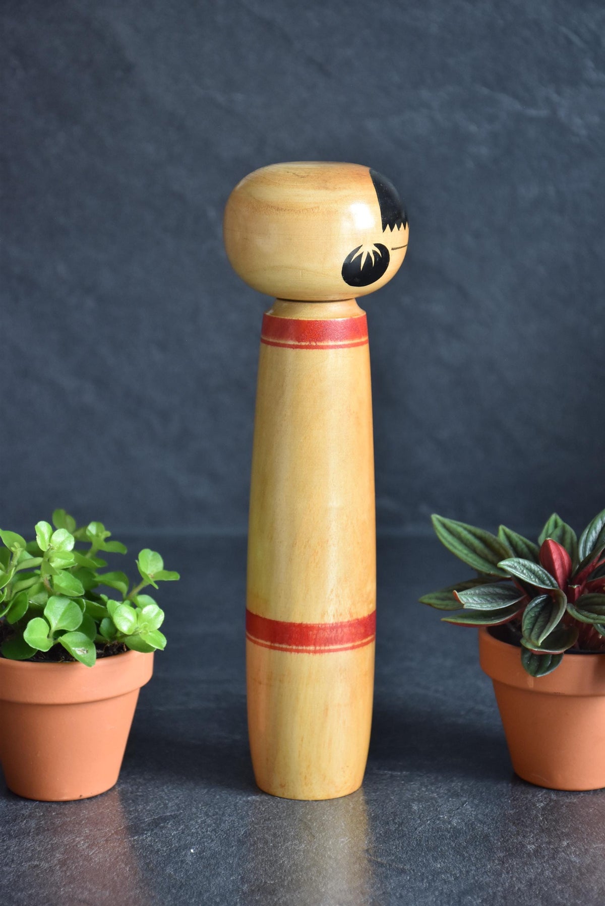 Sasaki Jinzaburo kokeshi doll standing upright with a focus on its slim, hand-painted silhouette