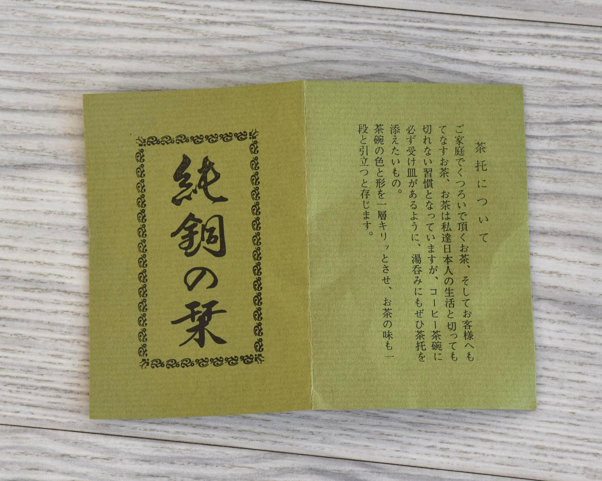 Shochikubai Hammered Copper Chataku Tea Set folded paper pamphlet with Japanese text on a wooden surface