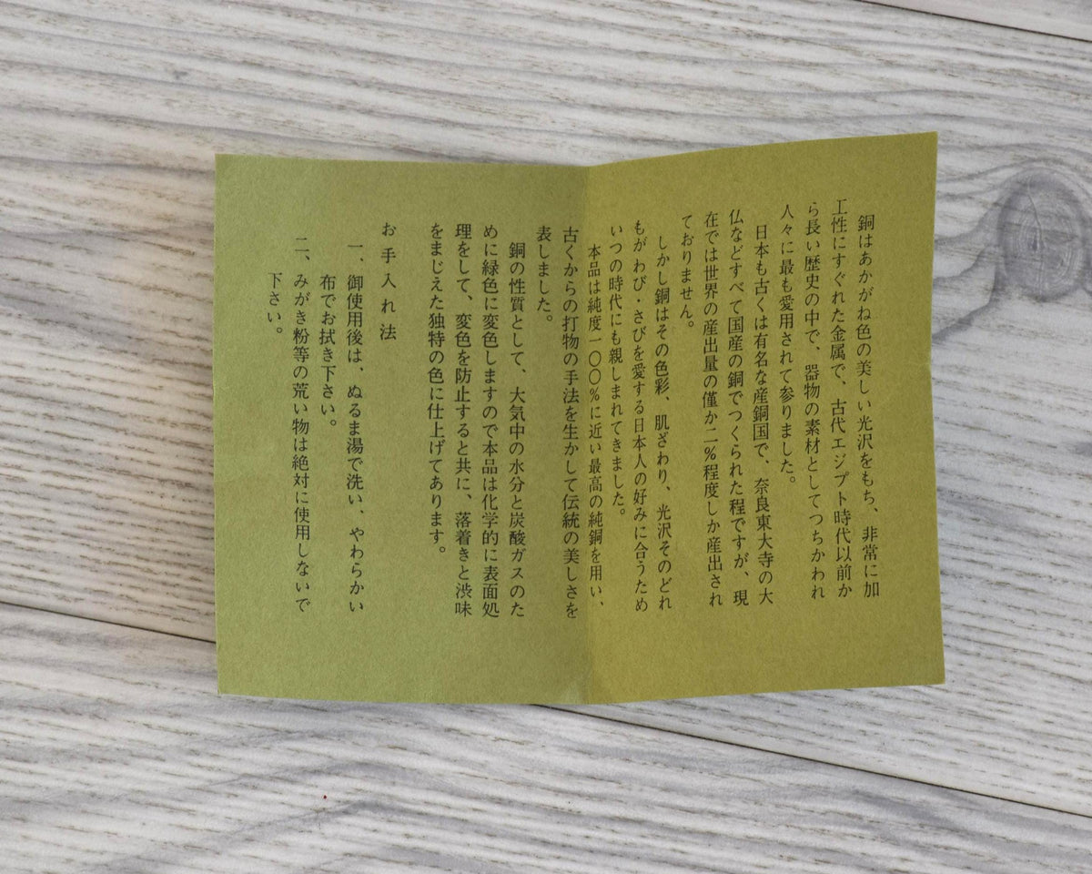 Shochikubai Hammered Copper Chataku Tea Set open Japanese instruction booklet resting on a wooden tabletop