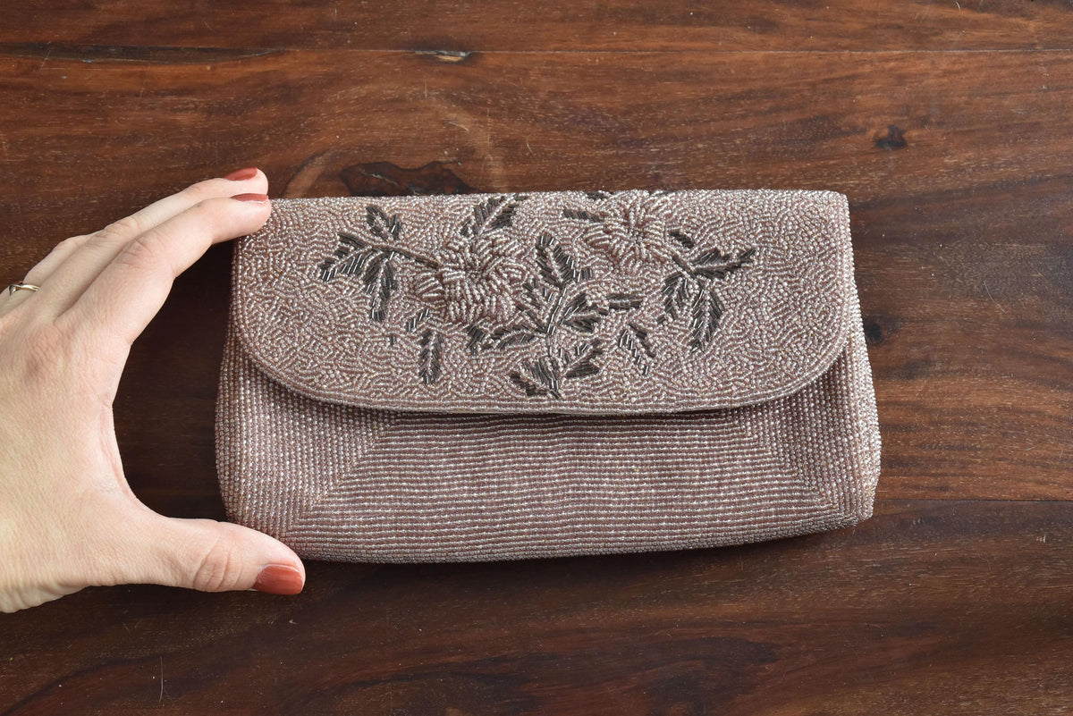 Japanese Floral Beaded Clutch In Lavender shown next to a hand for scale