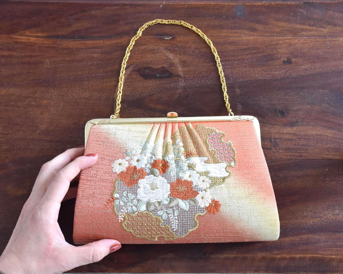 Floral Woven Kimono Clutch held next to a hand on a wooden surface for scale