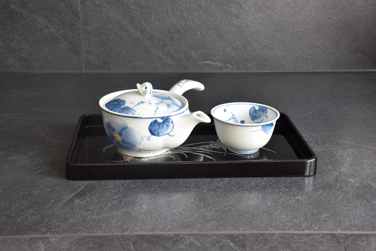 Black lacquer serving tray styled with a decorative blue and white ceramic teapot and teacup