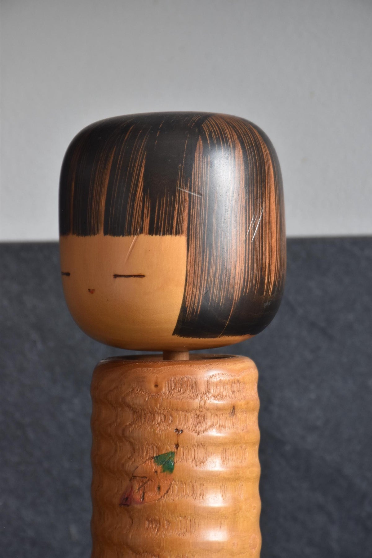 Usaburo Sosaku Kokeshi doll close-up of face with meditative expression and small facial scratch