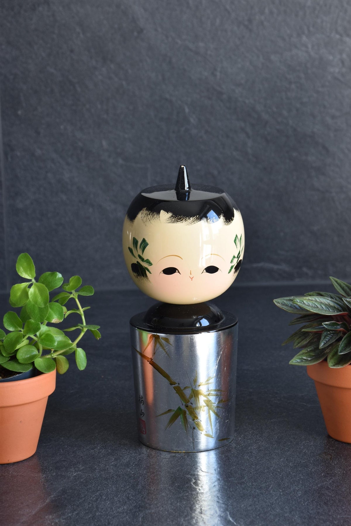 Hanawarabe kokeshi doll featuring a metallic foil body with hand-painted bamboo