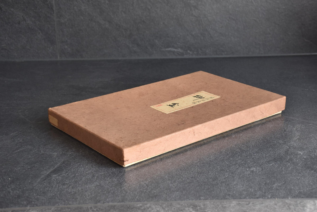 Original textured paperboard storage box with a labeled lid resting on a dark slate surface