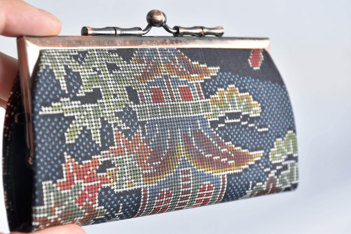 Blue Oshima Tsumugi Silk Gamaguchi Coin Purse held closely by a hand highlighting the metallic clasp and detailed weave
