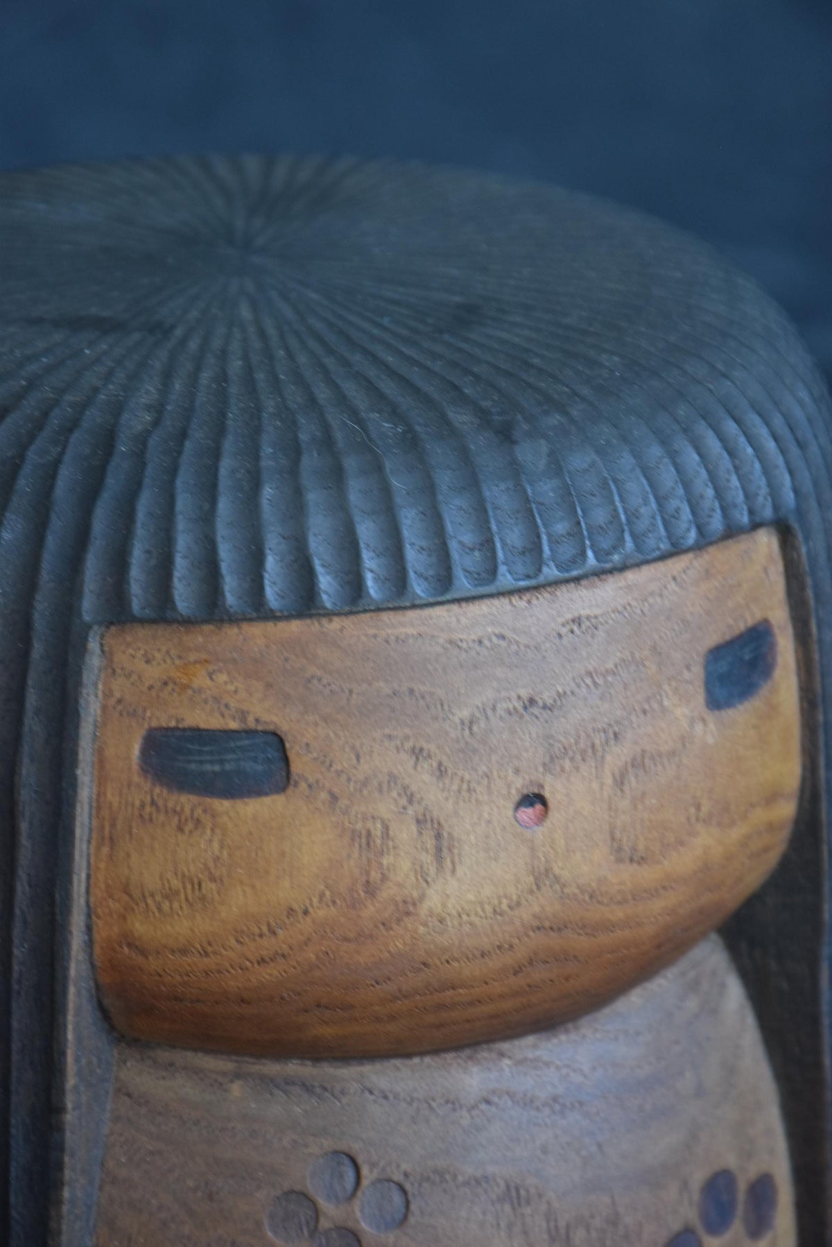 Sanpei Yamanaka kokeshi upper face and hair texture close-up in warm lighting