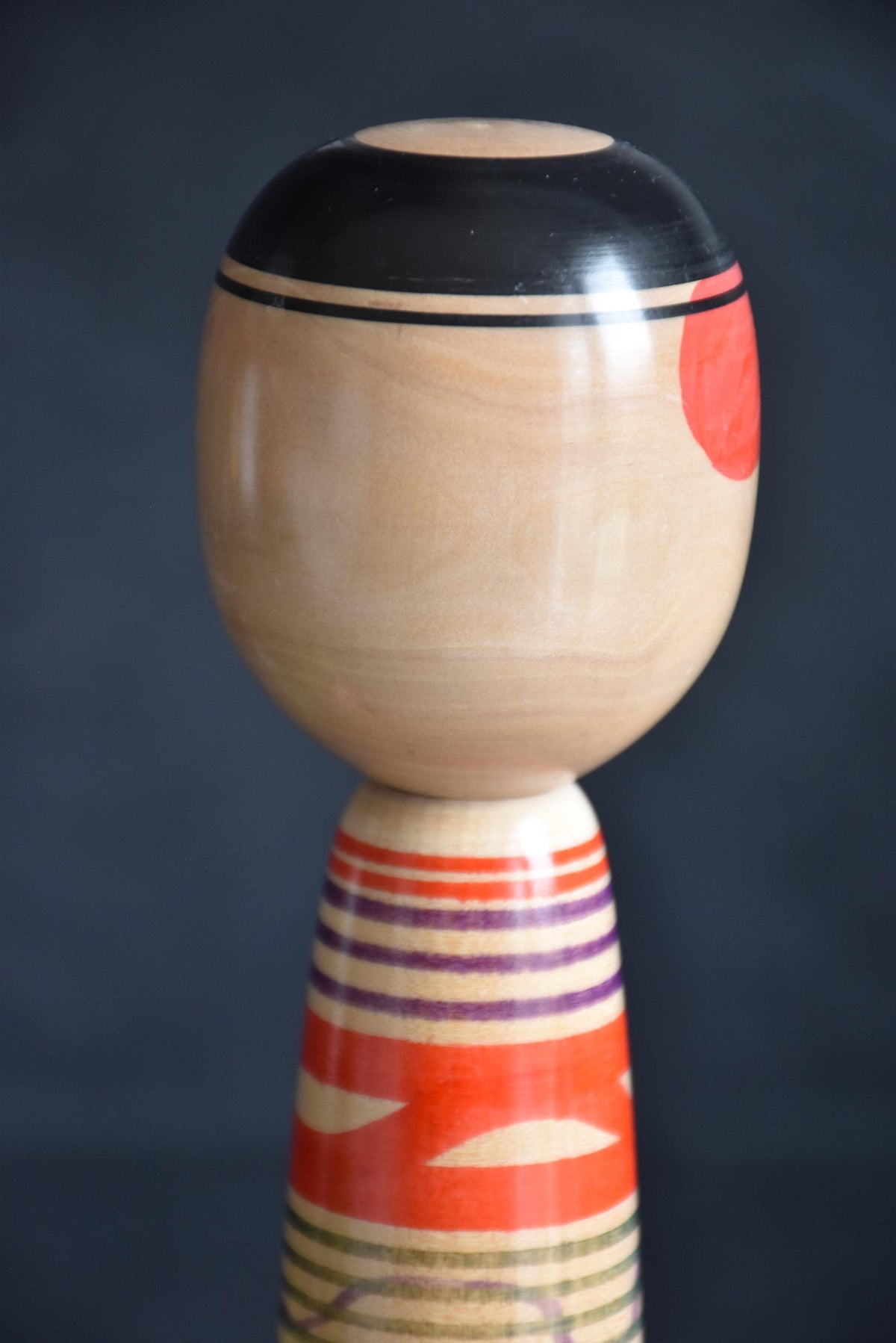 Tsuchiyu kokeshi doll back of the head showing black concentric circles and red motifs