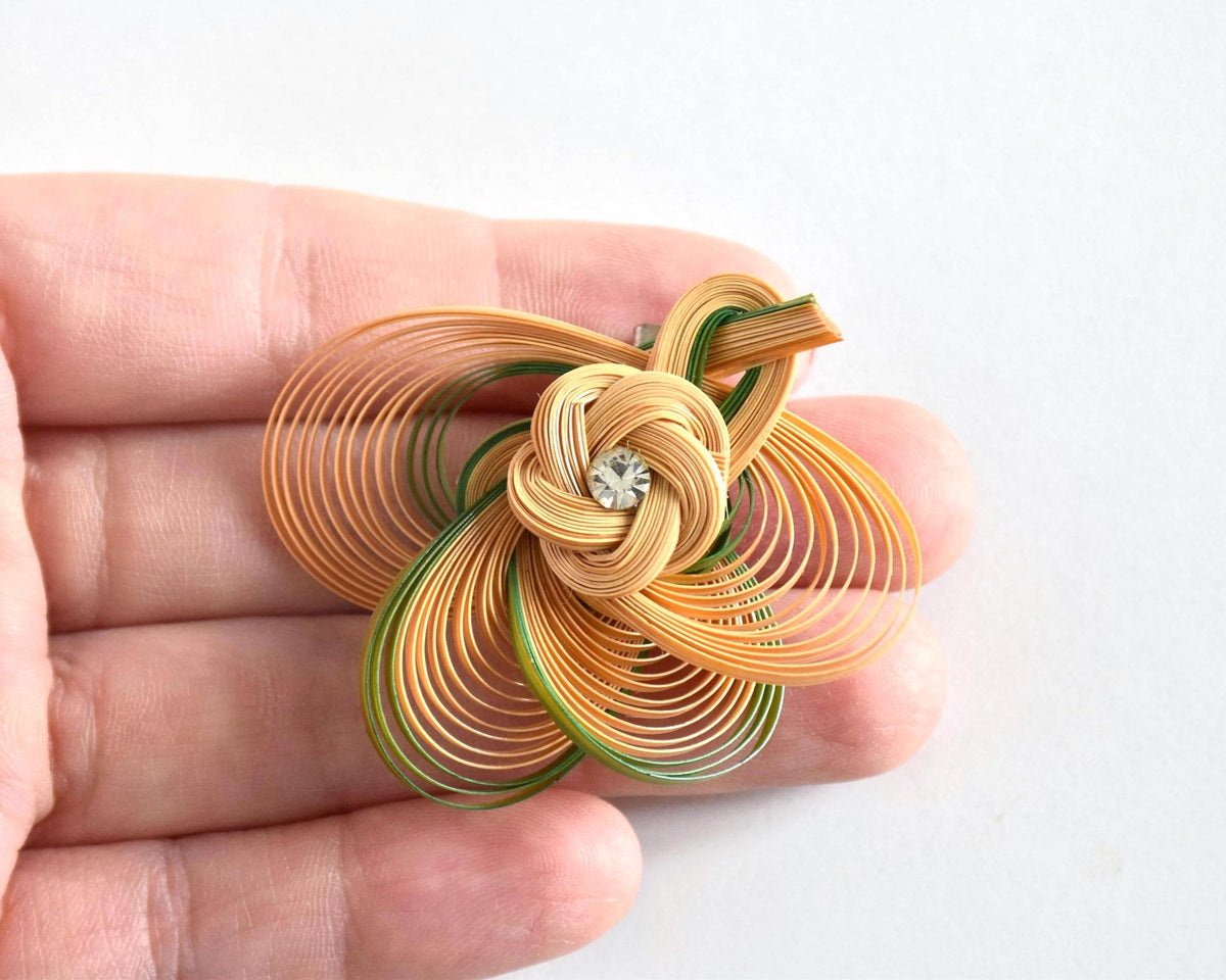 Hand-Woven Bamboo Knot Brooch In Beige And Green held in an open hand