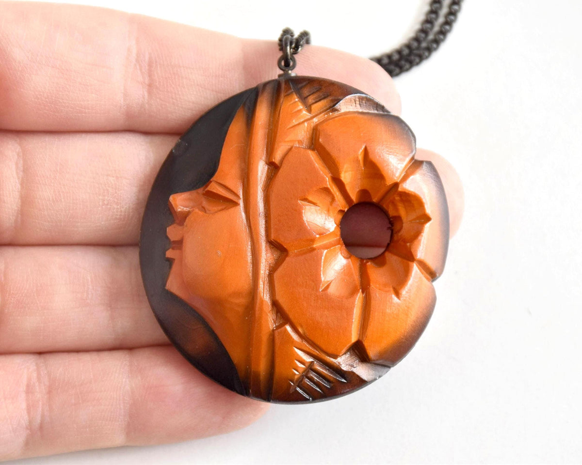 Ainu hand-carved wooden floral medallion necklace held in hand