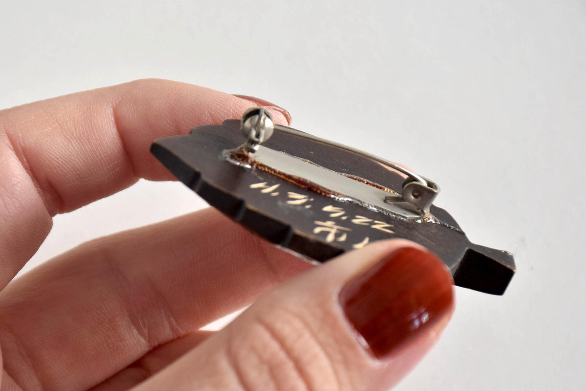 Close-up of Ainu leaf brooch back showing metal safety pin clasp mechanism