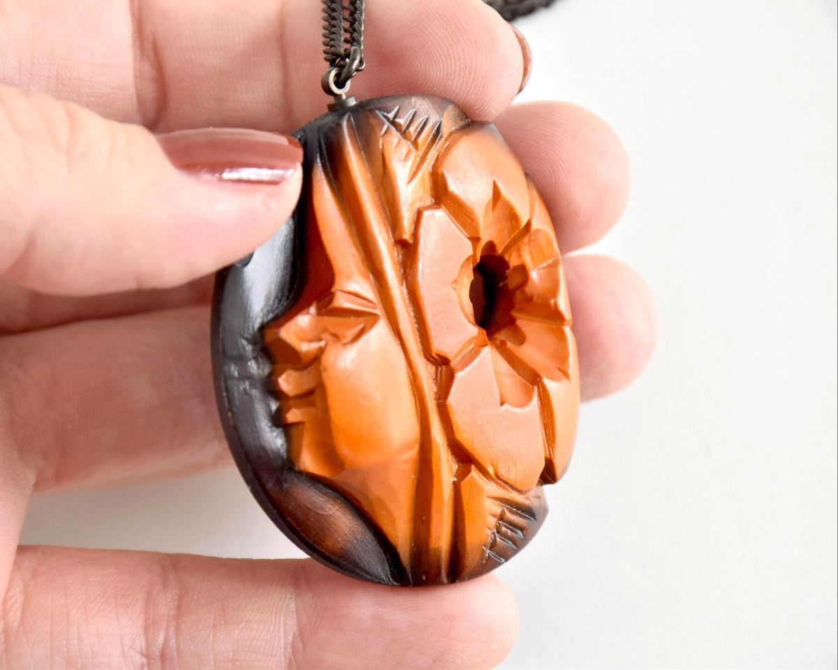 Ainu hand-carved wooden floral medallion necklace angled view in hand