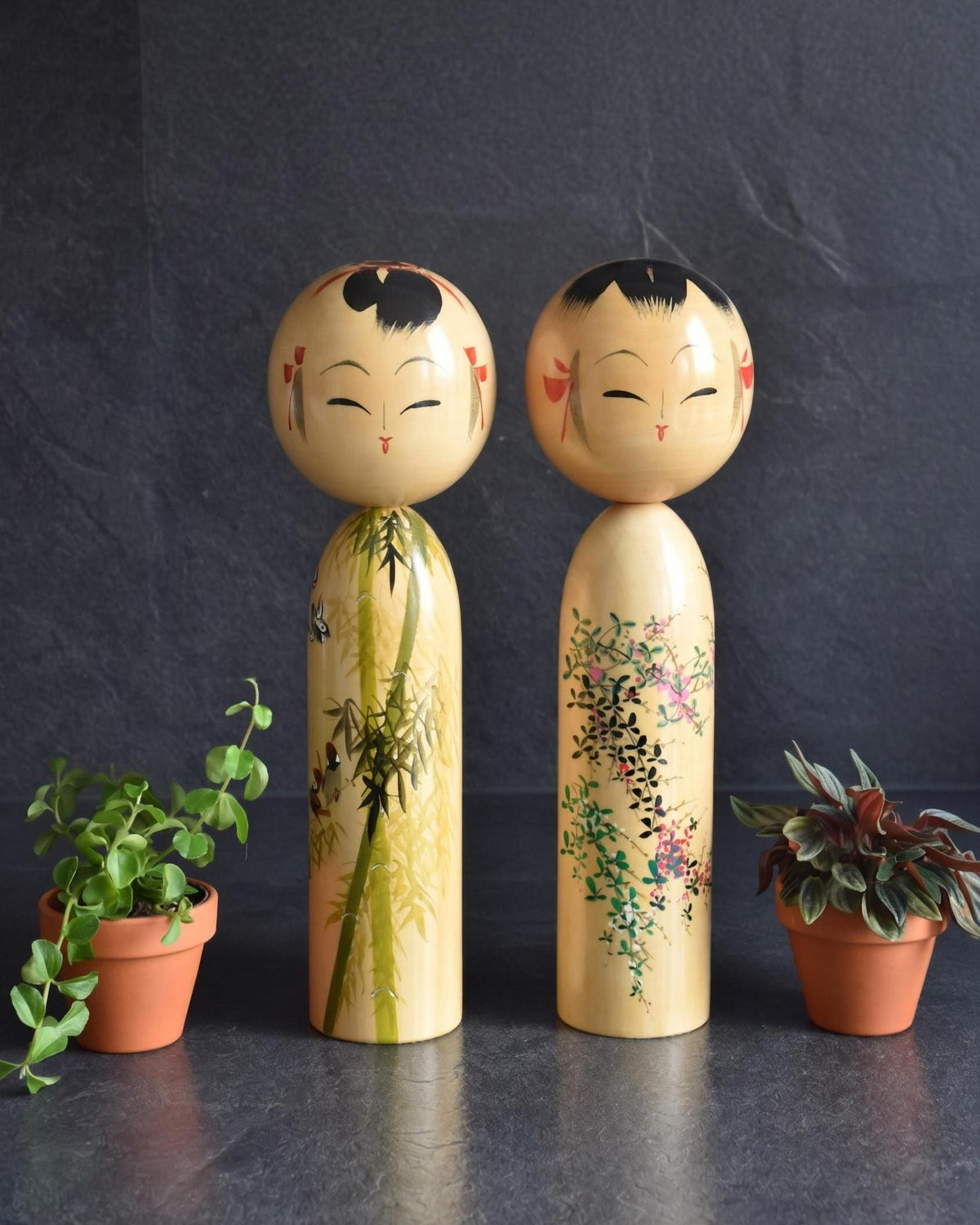Pair of Japanese kokeshi dolls bamboo and floral motif standing together