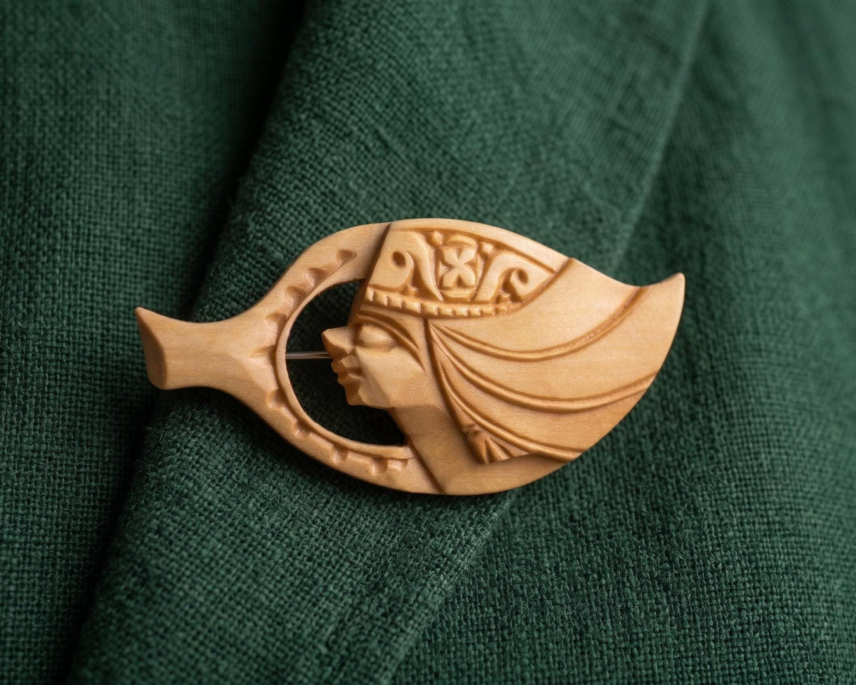 Ainu Hand-Carved Wooden Brooch Female Profile Leaf Shape pinned on green fabric